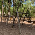Photo shows a woodland play area with wooden climbing frames for children to play on.
